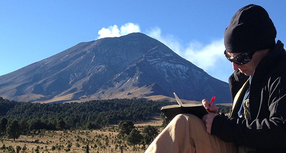 A scientist making notes in front of a volacano